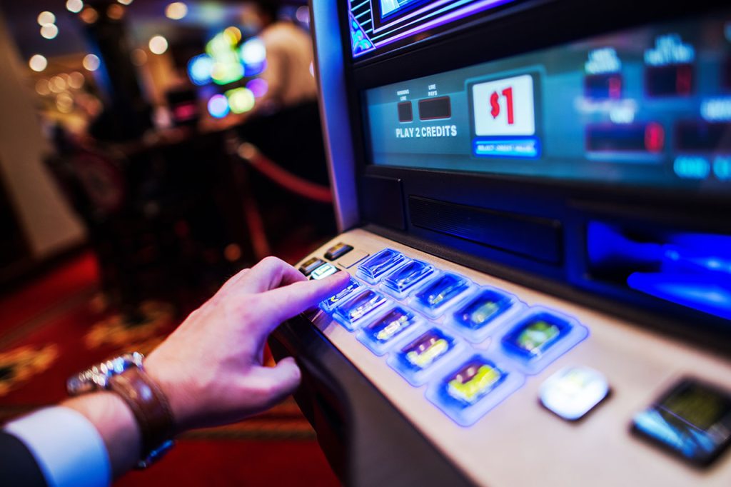  Picture of a man playing a slot machine.
